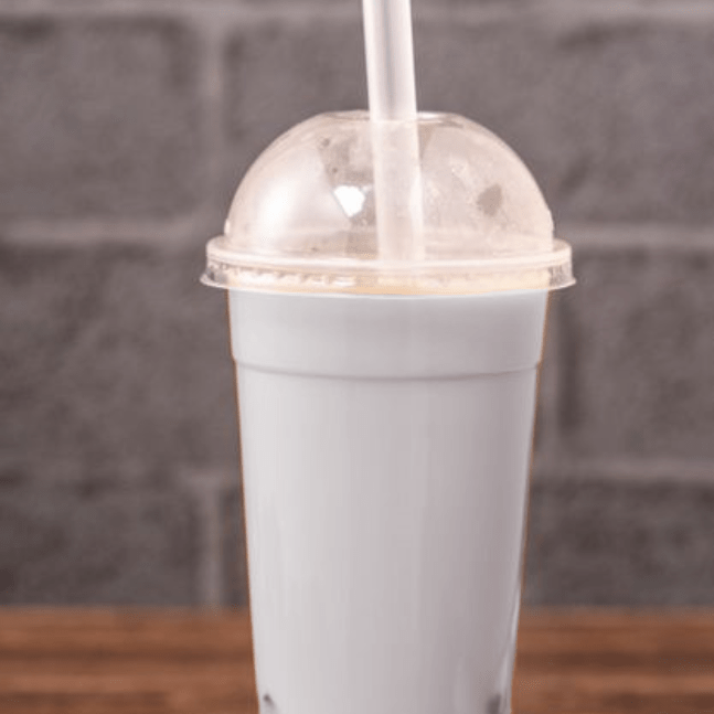 Cosmic Pearl bubble tea in a clear plastic cup on a gray brick background.